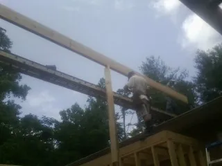 Carpenter setting a ridge beam over a new addition frame — Ice Dam Removal by Roofing Brothers in Concord